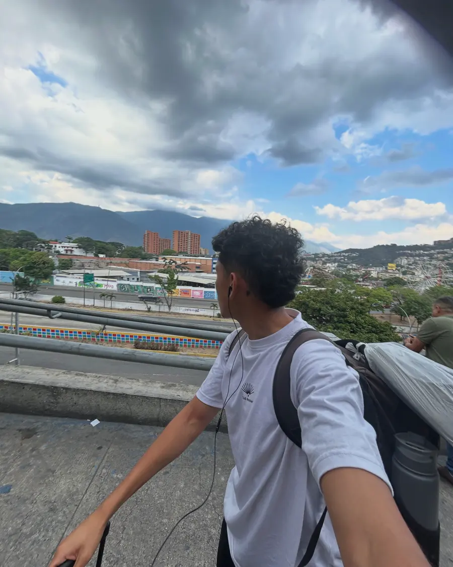 Dani con morral mira la ciudad desde una pasarela en Barquisimeto.