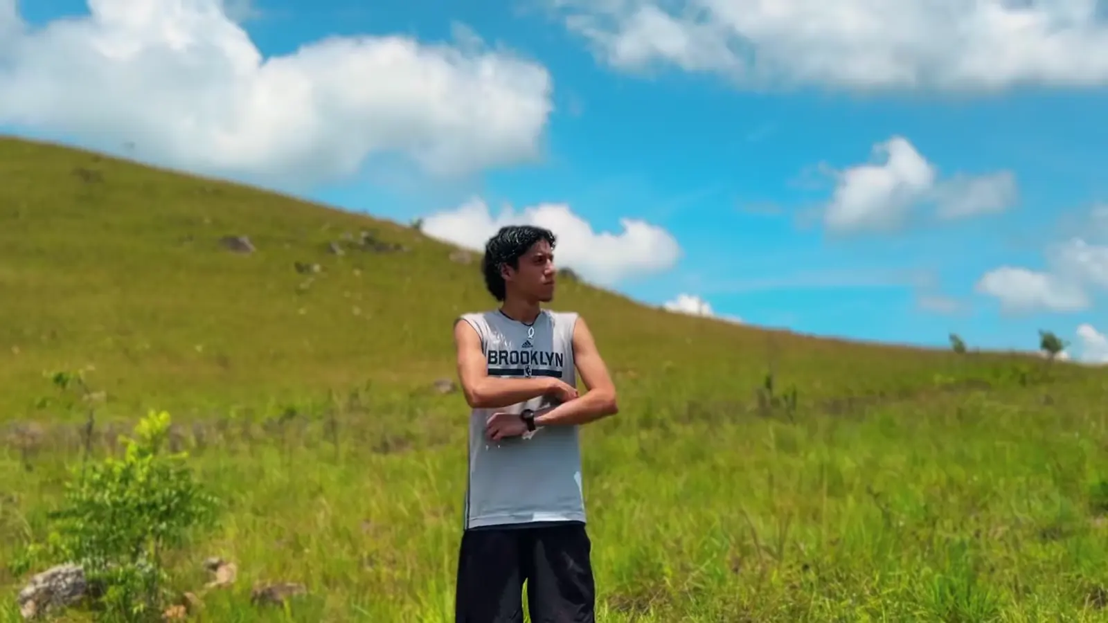 Cúa: un creador de brazos cruzados en una colina bajo el cielo azul.