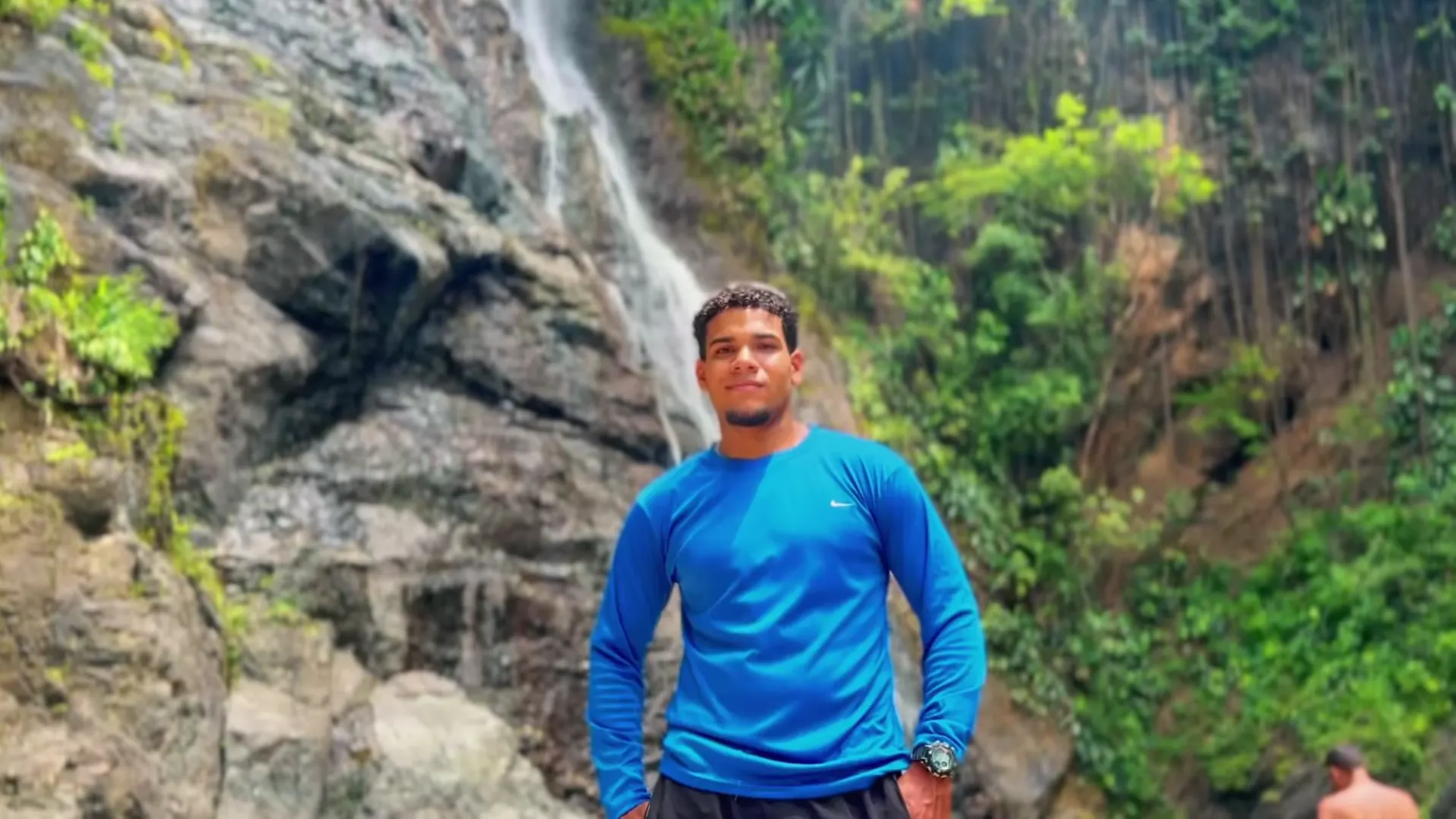 La Llovizna: @eliecer_ga con franela azul frente a la cascada.