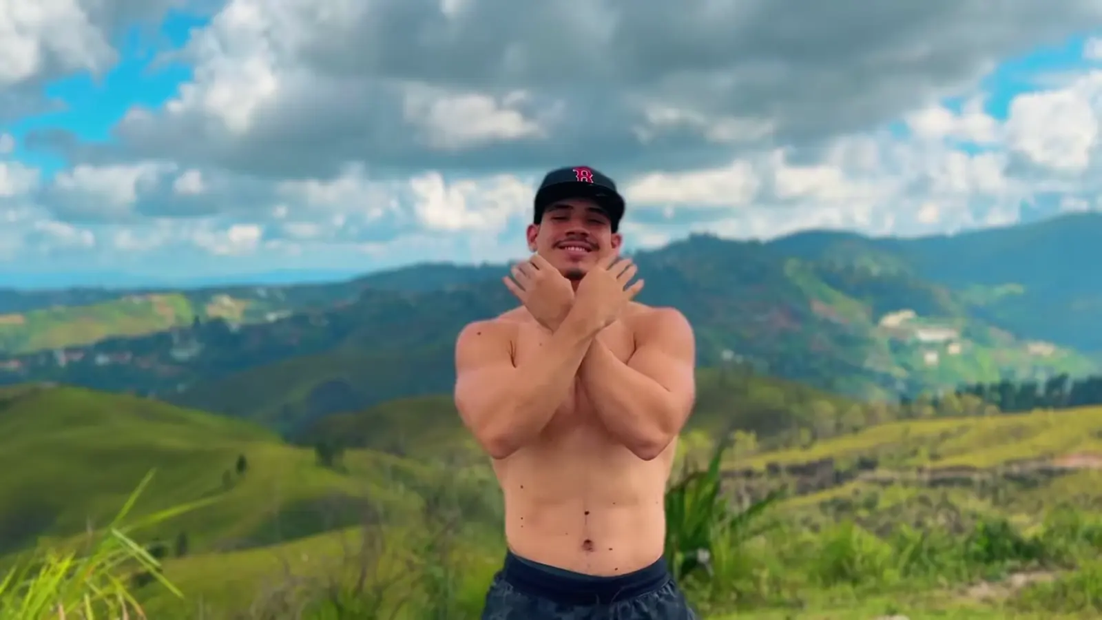 San Pedro: un creador con gorra cruza los brazos frente a las montañas.